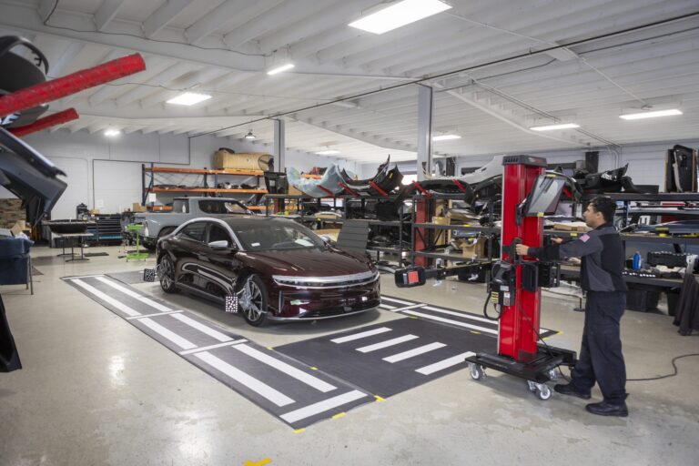 Technician performing luxury auto body repair on a high-end vehicle in Oceanside CA